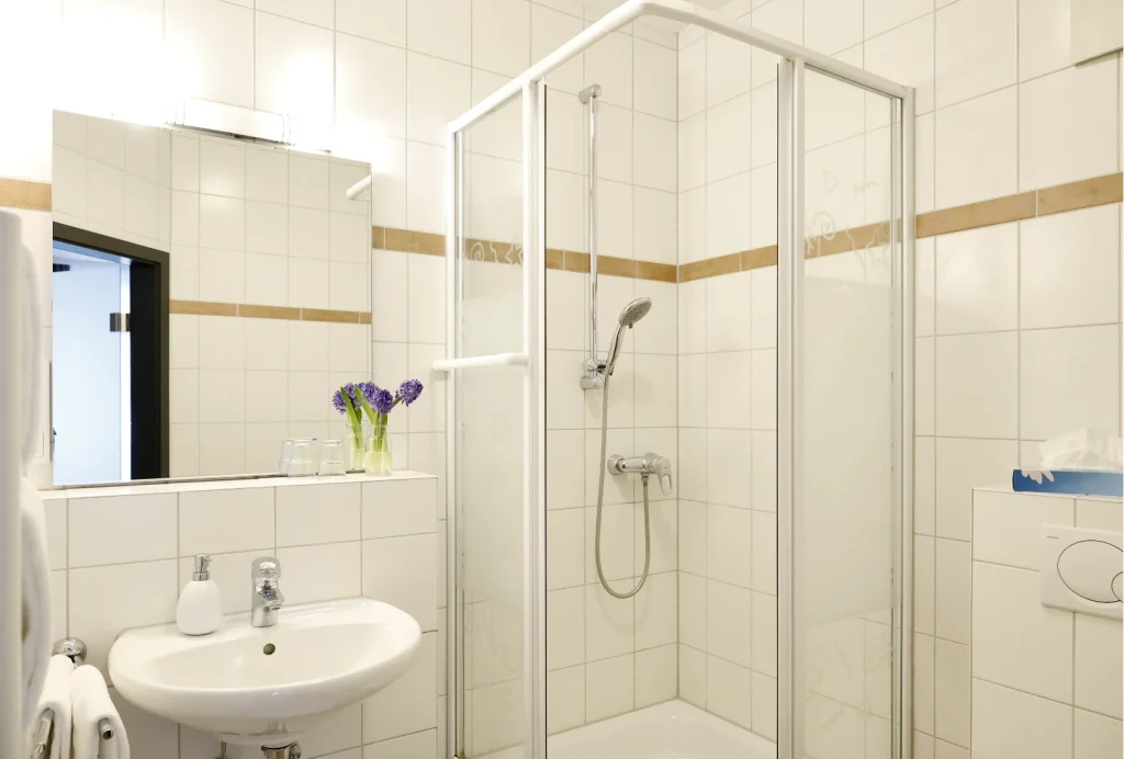 Kleines Badezimmer mit Duschkabine, Waschbecken, Spiegel und Handtüchern