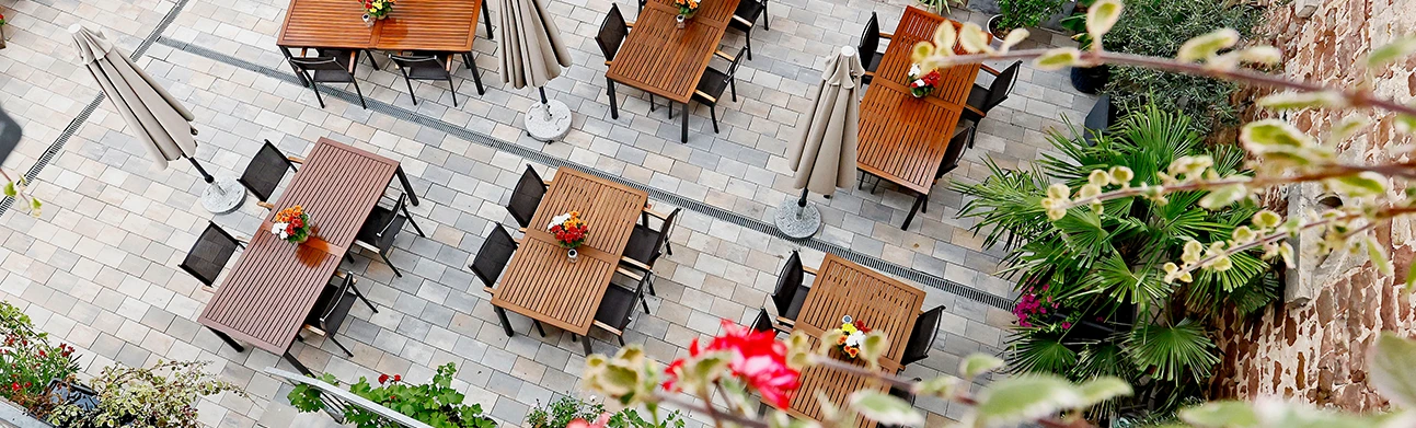 Außenterrasse mit gedeckten Tischen und bunten Blumen im Innenhof des Vinotel Weinstraße
